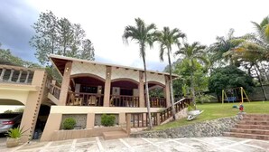 Un edificio de dos pisos con un balcón, una escalera y un arenero en el patio.