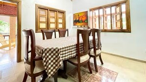 Un comedor con una mesa y sillas de madera, mantel a cuadros y un cuadro en la pared.