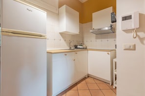 Una cocina compacta con refrigerador, estufa y microondas.