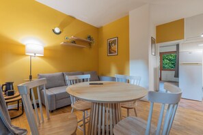 Un comedor con una mesa redonda de madera, seis sillas, un sofá y una lámpara.