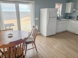 A kitchen with a refrigerator, microwave, and wooden dining table with chairs. - Sunkissed Resort (Oscoda)