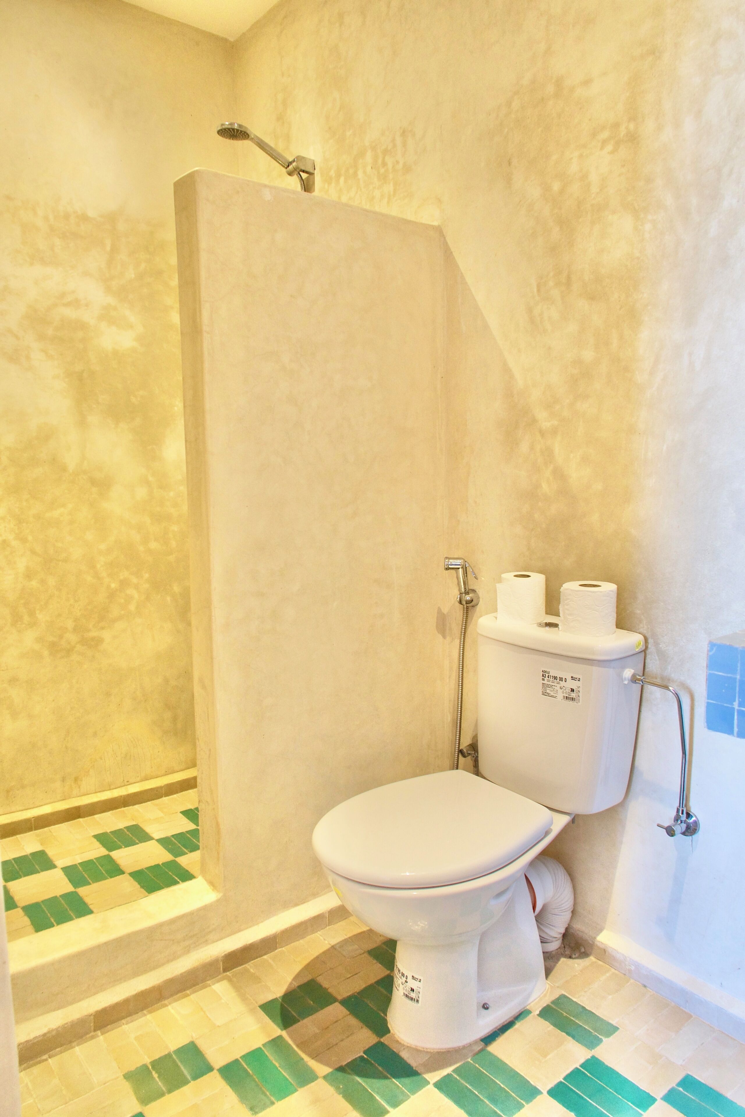 A bathroom with a shower, toilet, and tiled floor.