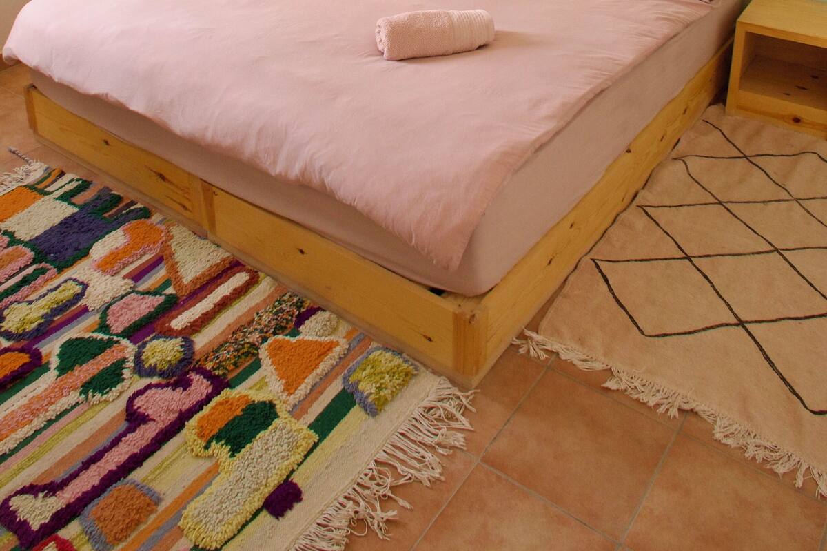 Ein Einzelbett mit Holzbettgestell, einem Kopfteil und einem passenden Nachttisch.