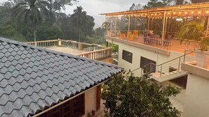 Ein mehrstöckiges Gebäude mit Dachterrasse, Sitzgelegenheiten im Freien und Blick auf die umliegenden Bäume.