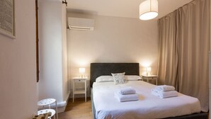 Un dormitorio con una cama grande, lámparas de noche, una mesita y un equipo de aire acondicionado.