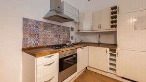 Una cocina con gabinetes blancos, salpicadero de azulejos, estufa a gas y horno empotrado.