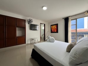 A hotel room with a bed, a TV, a bathroom, and a view of the outside. - Hotel Suite Santa Rosa (Santa Rosa de Cabal)