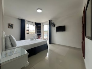Une chambre d’hôtel avec un lit, une table de chevet, une télévision et une fenêtre donnant sur un beau paysage.