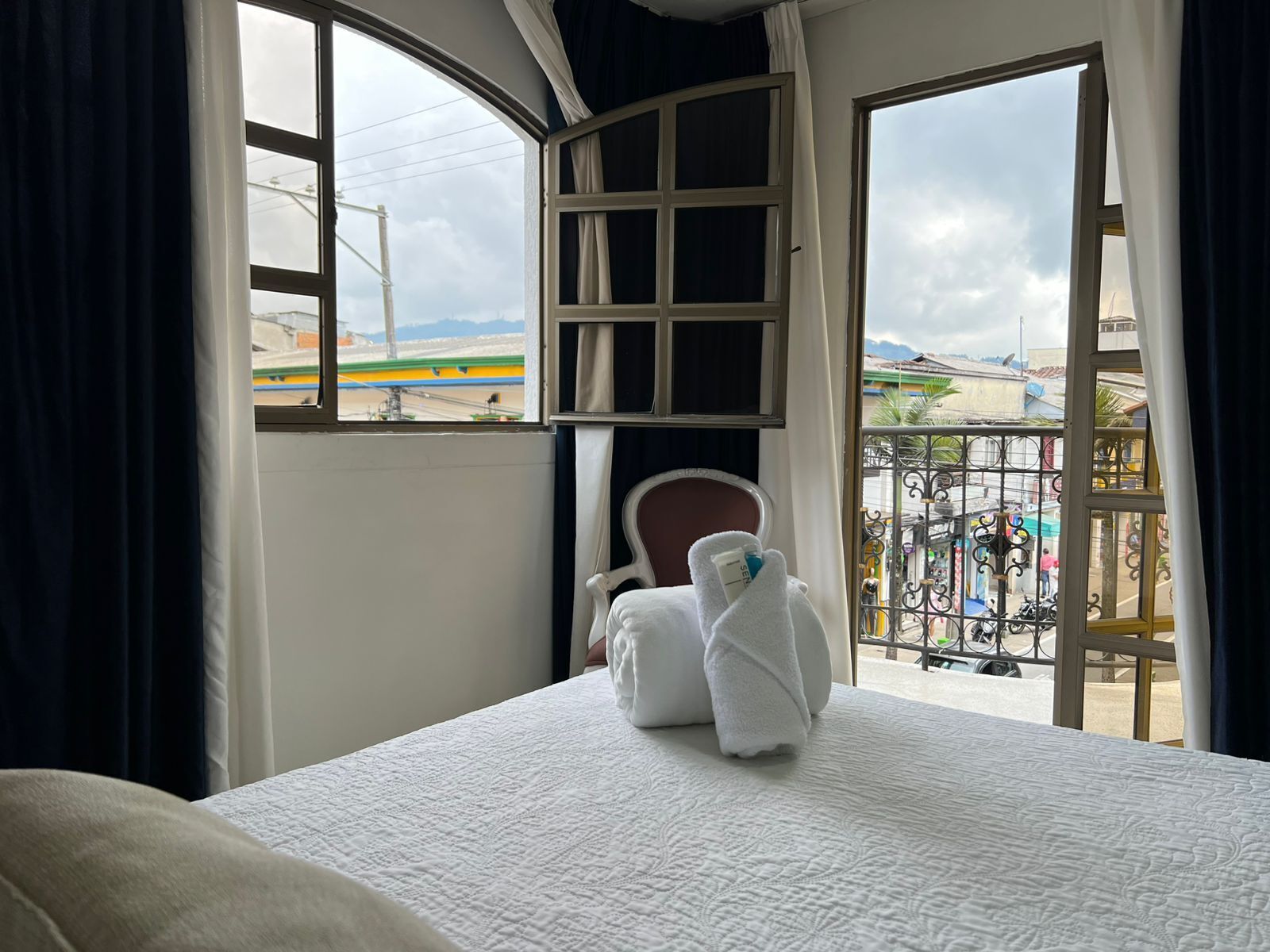 A hotel room with a bed, a chair, and a view of a beach and airport.