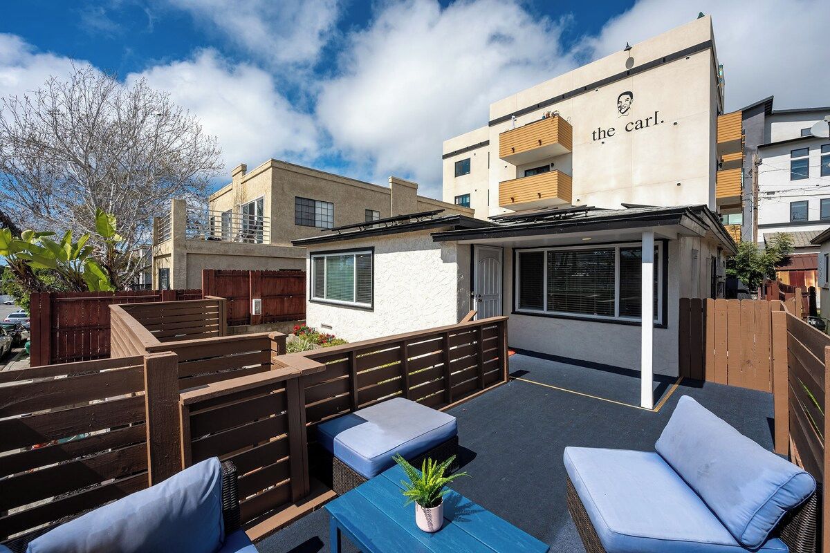 An outdoor seating area with wooden benches and a blue table, surrounded by a wooden fence.