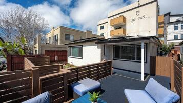 An outdoor seating area with wooden benches and a blue table, surrounded by a wooden fence.