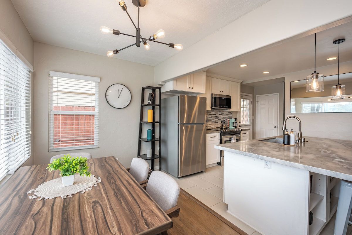 A modern kitchen with a central island, stainless steel appliances, and pendant lighting.