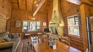 A log cabin interior with a dining area, a fireplace, and a television. - Log Cabin Home  3 Private Acres (Wimberley)