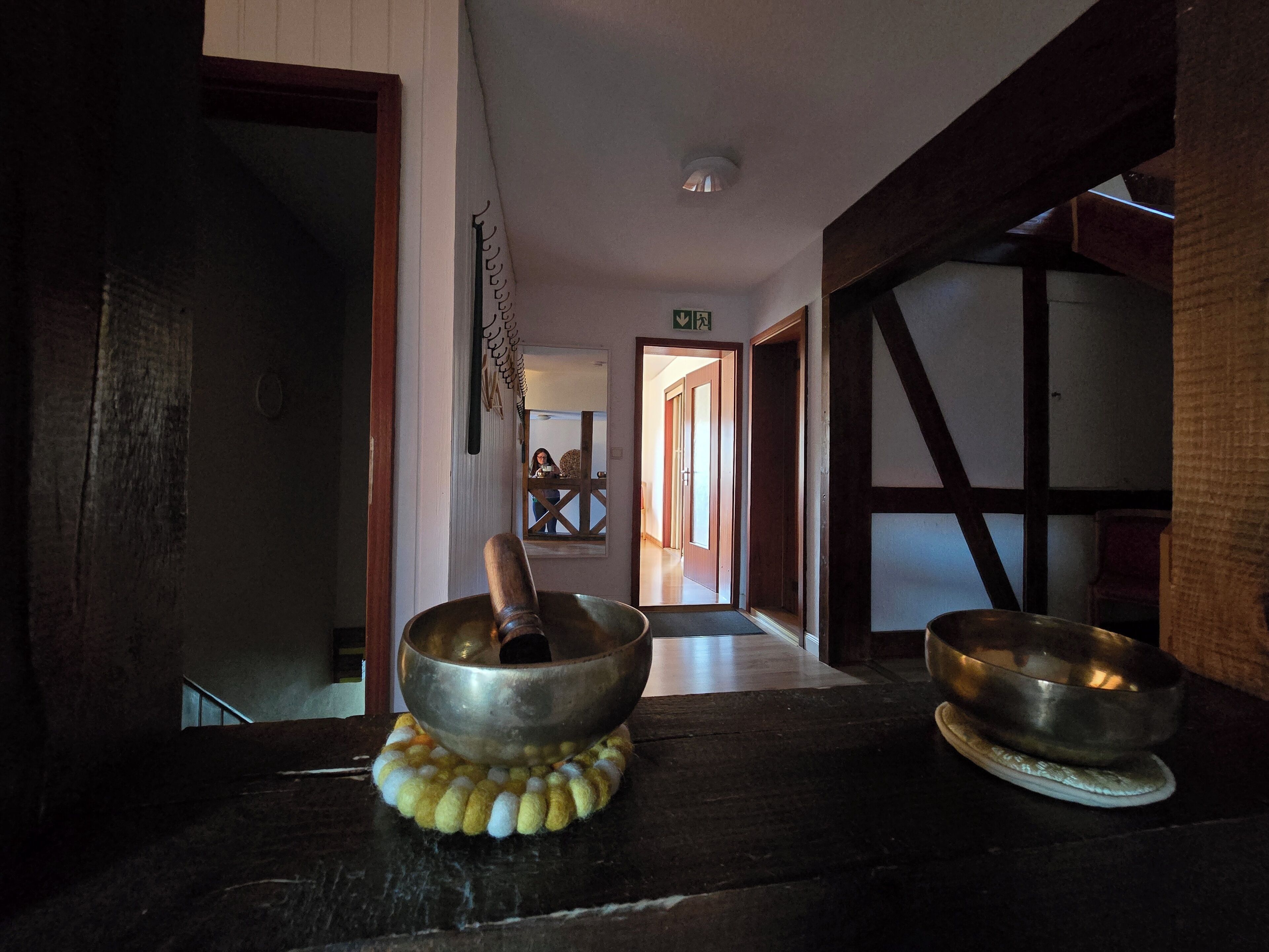 En inredning med träpaneler och en traditionell japansk shoji-skärm, ett träbord med en skål av metall och en trappa i trä.