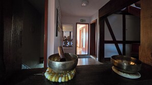 Un interno in legno con un tradizionale schermo giapponese shoji, un tavolo in legno con una ciotola in metallo e una scala in legno.