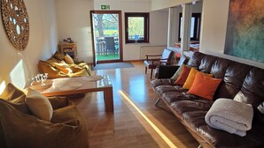 Un'ampia zona giorno con un divano in pelle, un tavolino in legno e un pouf marrone.