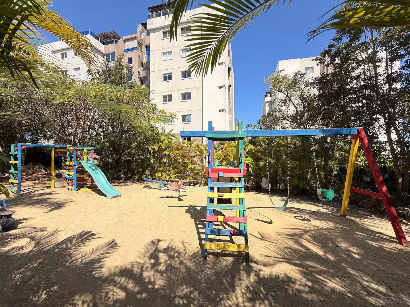 Ein Spielplatz mit Rutsche, Schaukeln und Klettergerüsten.