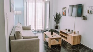 A modern living room with a sofa, coffee table, TV, and decorative items. - 'Stoa Apartment' at Rethymno center (Rethymno)
