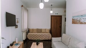 A modern living room with a sofa, a coffee table, a TV, and a painting on the wall. - 'Stoa Apartment' at Rethymno center (Rethymno)