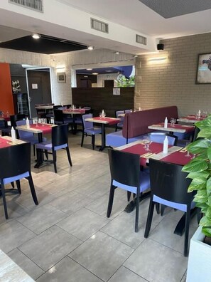 A restaurant interior with tables and chairs, a brick wall, and a ceiling with recessed lighting. - Hotel Restaurant Vesontio (Besançon)