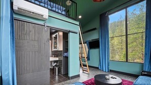 A room with a bunk bed, a ladder, a window with curtains, and a small round table.