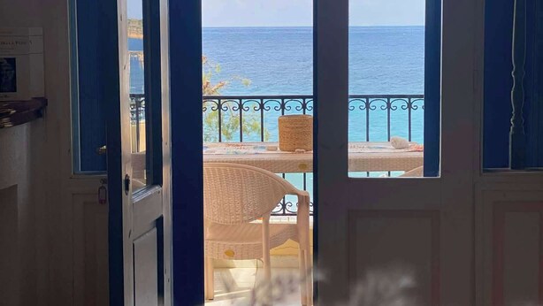 Una stanza con vista sul mare attraverso una porta vetrata.