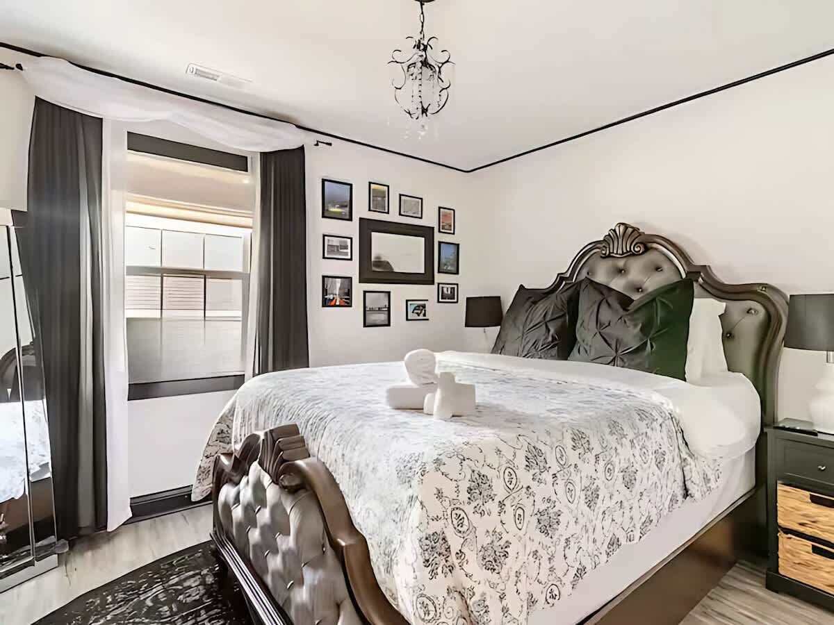 Une chambre à coucher avec un grand lit, un lustre, un miroir et un mur orné de tableaux.