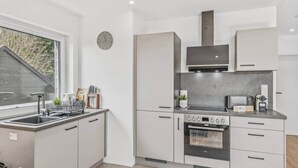 Une cuisine moderne équipée d’un four encastré, d’un four à micro-ondes et d’une plaque de cuisson.