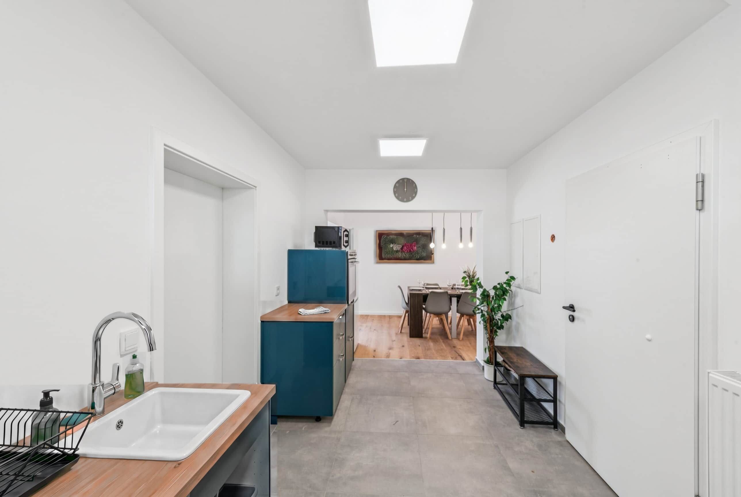 Un pasillo estrecho con una cocina a la izquierda, un comedor en el centro y un salón a la derecha.