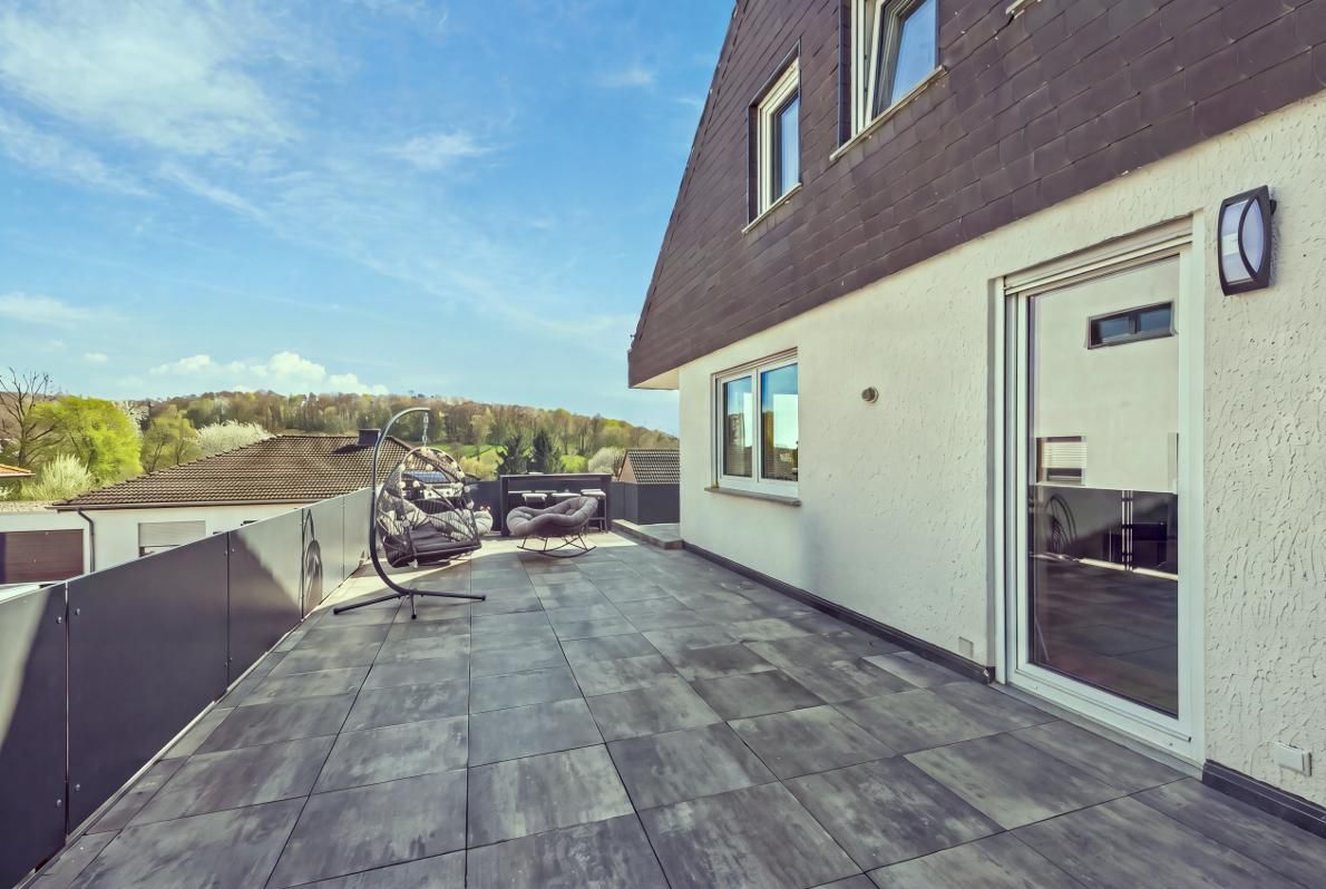 Eine Dachterrasse mit Blick auf die Landschaft, eine Pergola und Gartenmöbel.