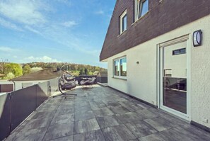 Eine Dachterrasse mit Blick auf die Landschaft, eine Pergola und Gartenmöbel.