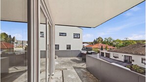 En moderne bygning med terrasse, grill og et overdækket område.
