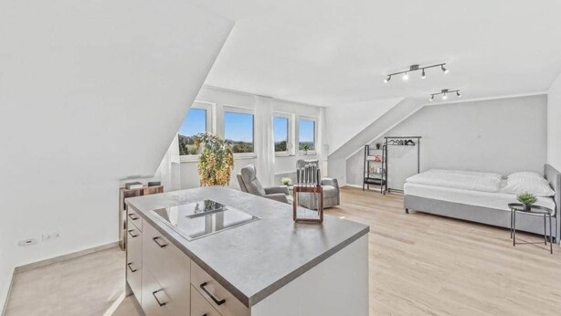 Un dormitorio tipo loft moderno con una cama grande, una kitchenette y vistas al cielo.