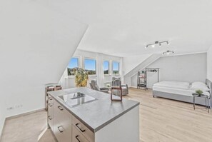 A modern loft bedroom with a large bed, a kitchenette, and a view of the sky. - 15-minute drive | Views extending to Luxembourg · Cinema & Luxury (Trierweiler)