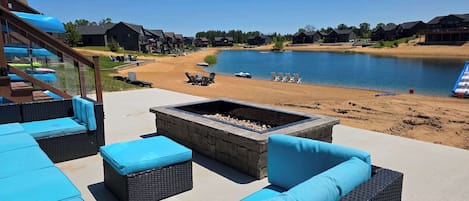 Un patio con mobiliario exterior, una chimenea y vistas a un lago y una playa.