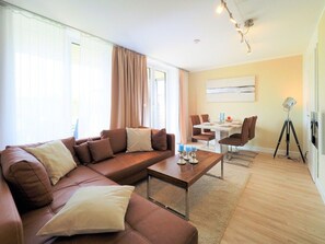 A modern living room with a brown sofa, a coffee table, and a dining area with chairs and a table. - Peace and relaxation on the Baltic Sea between Boltenhagen and Wismar (Hohenkirchen, Meckl (Alt Jassewitz))