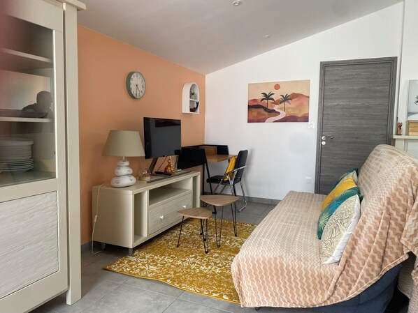 Une chambre à coucher avec un lit, un bureau avec une télévision, une chaise, une horloge et une porte.