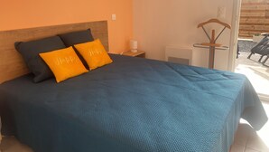 Et soveværelse med en seng, to puder, et natbord, en lampe og udsigt til et udendørs område.