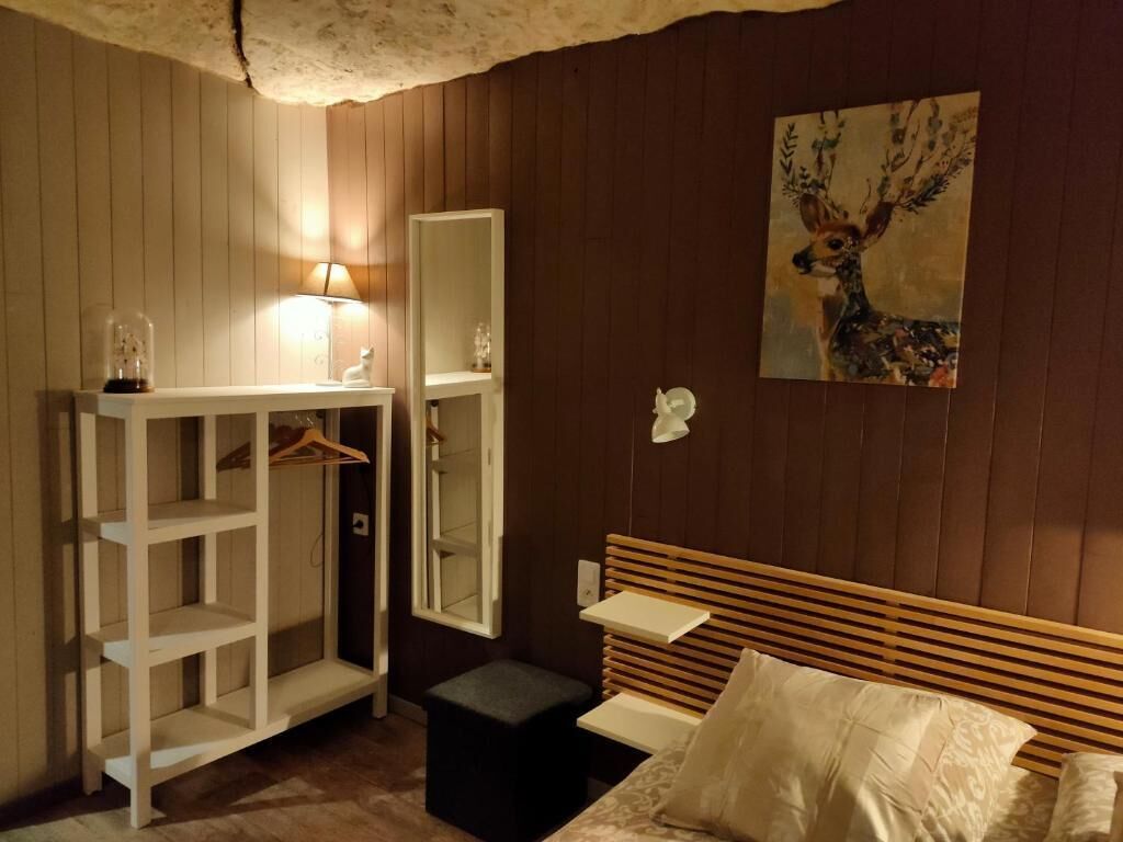 A bedroom with a bed, a white wardrobe, a mirror, and a painting on the wall.