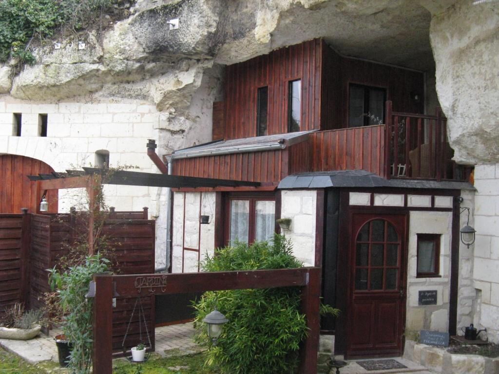 A rustic building with a wooden facade, a balcony, and a small garden area.