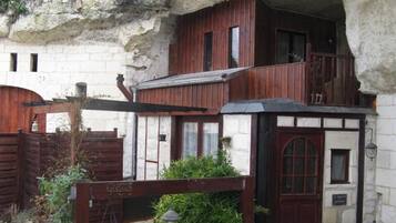 A rustic building with a wooden facade, a balcony, and a small garden area.