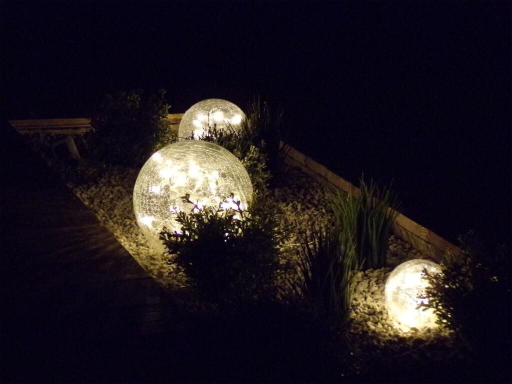 Estructuras esféricas iluminadas en un jardín nocturno.