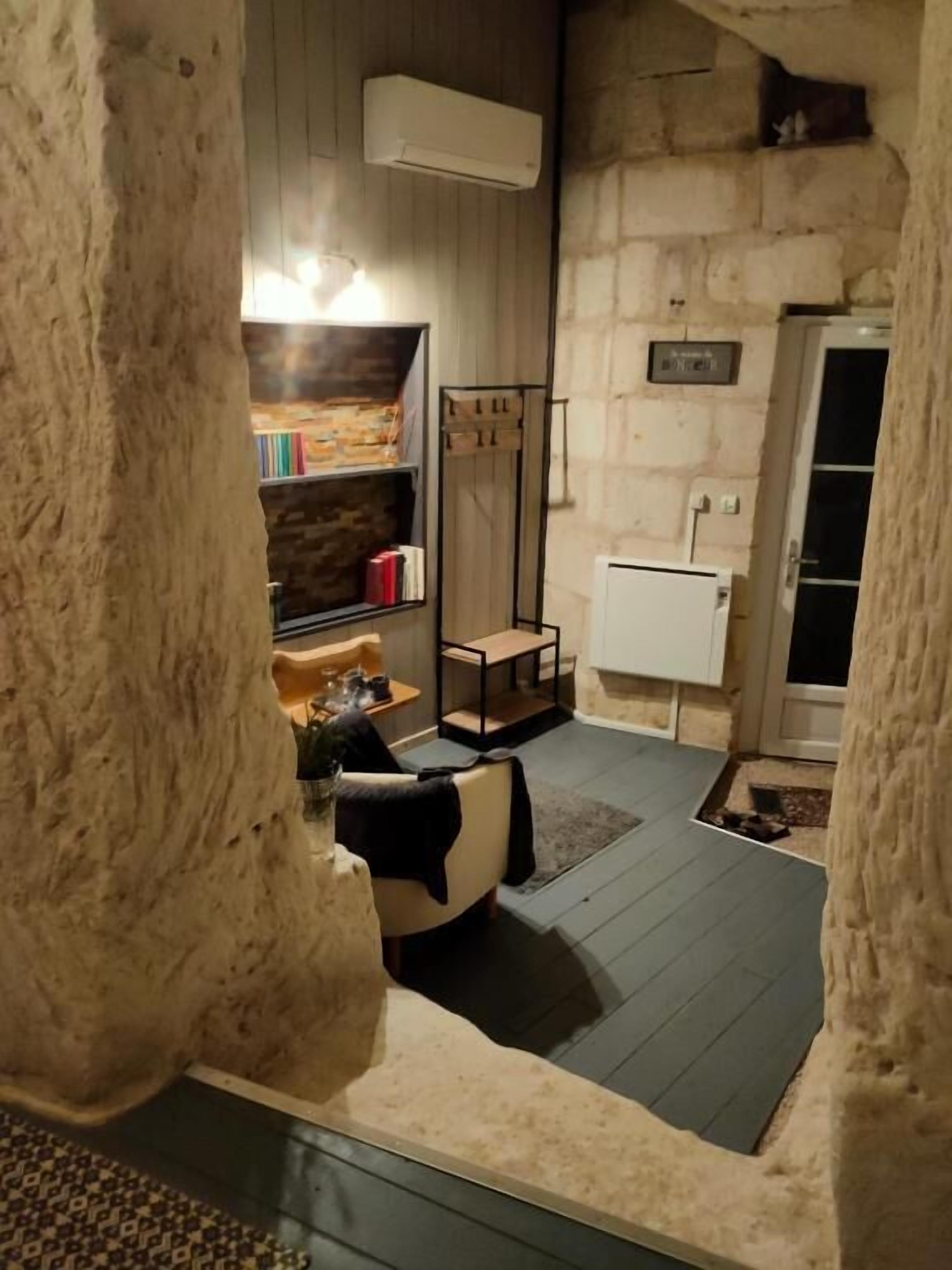 Ein Zimmer mit Steinwänden, einem Bett, einem Bücherregal, einem Heizkörper und einer Tür.