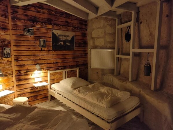 Una habitación con pared de madera, una cama, una mesita de noche, una lámpara y un radiador.