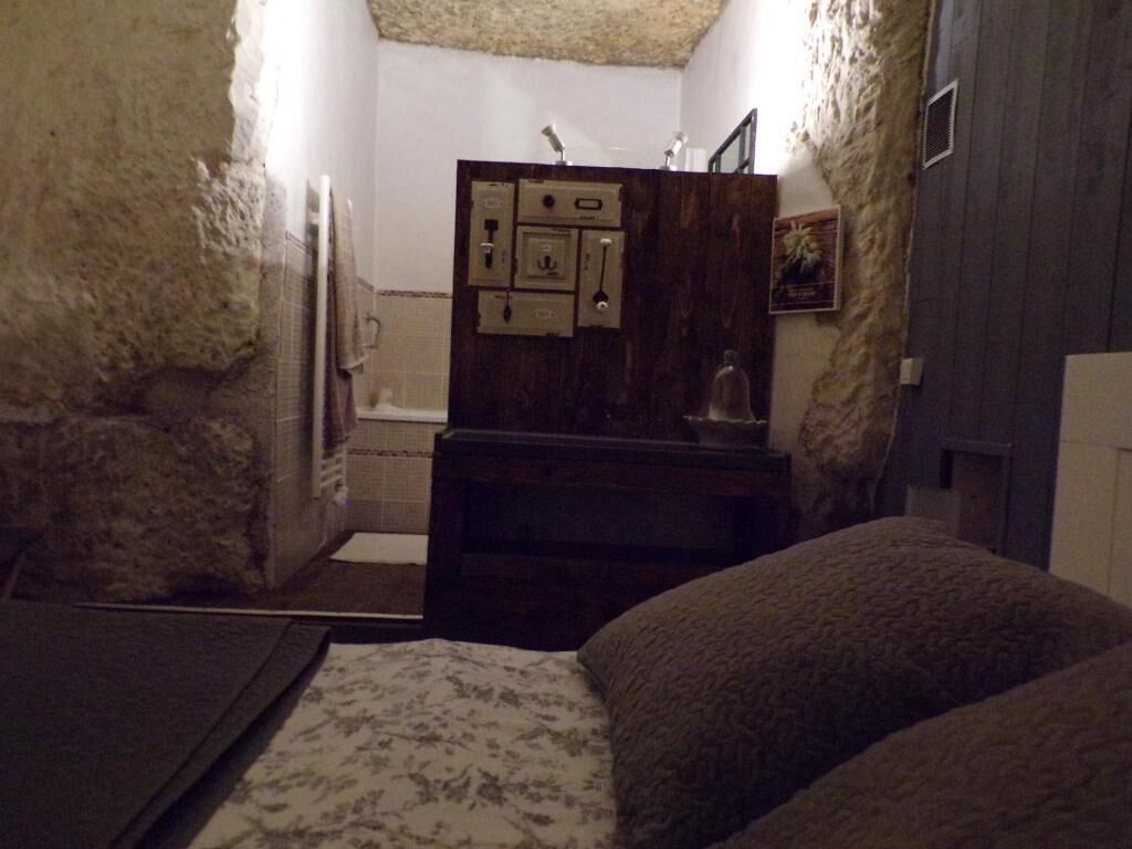 A narrow room with a bed, a wooden dresser, and a small window.