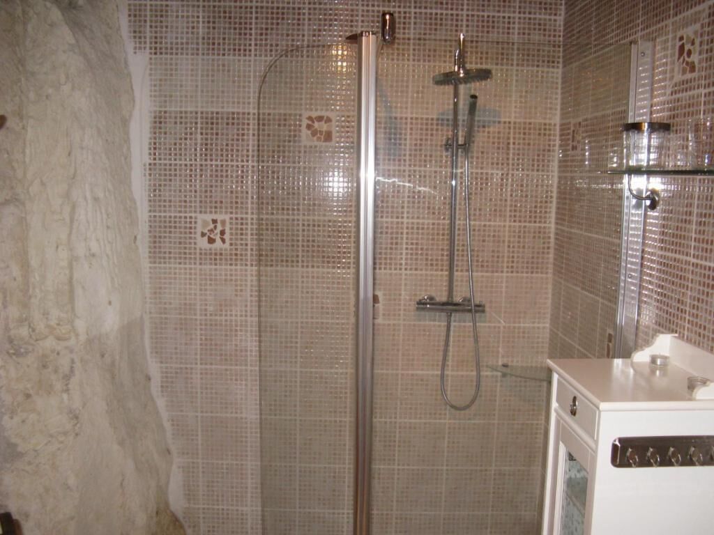 A shower with a glass door, a handheld showerhead, and a wall-mounted faucet.