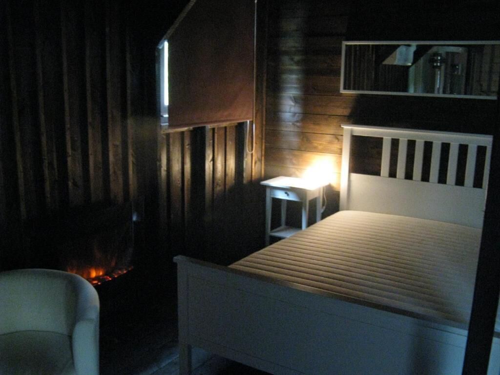 Een kamer met een bed, een tafeltje, een stoel en een open haard.