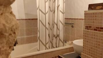 A bathroom with a bathtub, a sink, and a mirror.