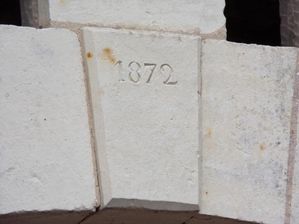 En vit stenmur med siffran ’1872’ inristad i den.