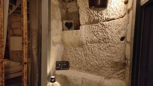 Una pared de piedra con una maceta colgante, un adorno con forma de corazón y un cartel con texto.